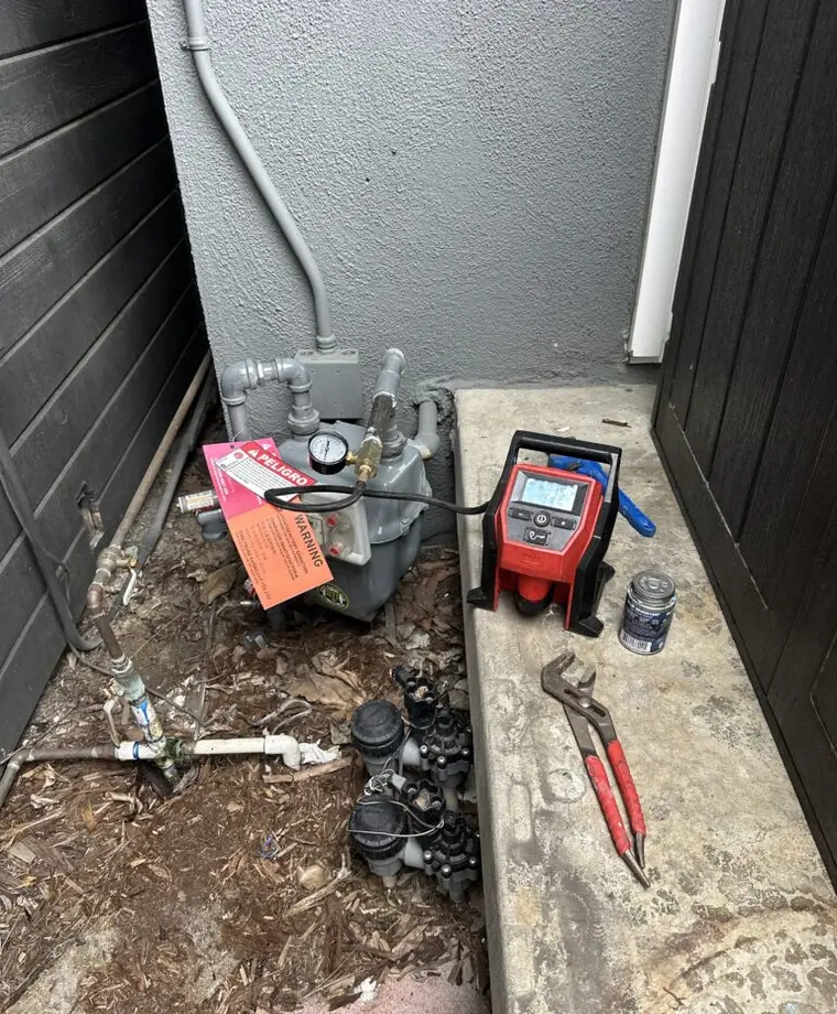 Technician performing professional gas leak detection testing on accessible piping